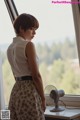 A woman standing in front of a window with a fan.