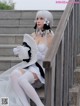 A woman in a white dress and hat sitting on some steps.