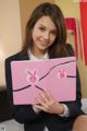 A woman in a business suit holding a pink book.