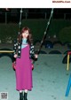 A woman standing on a swing in a park.